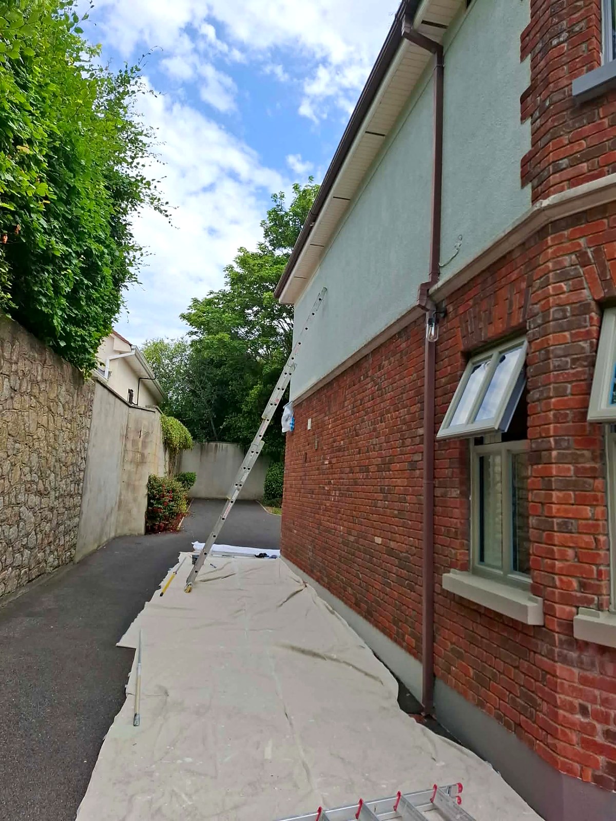 Side passage of the house showing painted render, gutters and downpipes with dust sheets down