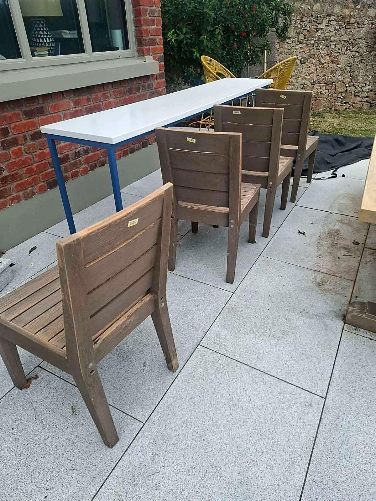 Set of weathered outdoor dining chairs lined up before repainting
