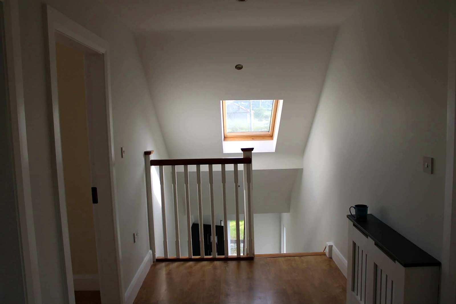 Bright landing under a skylight with freshly painted walls and balustrade