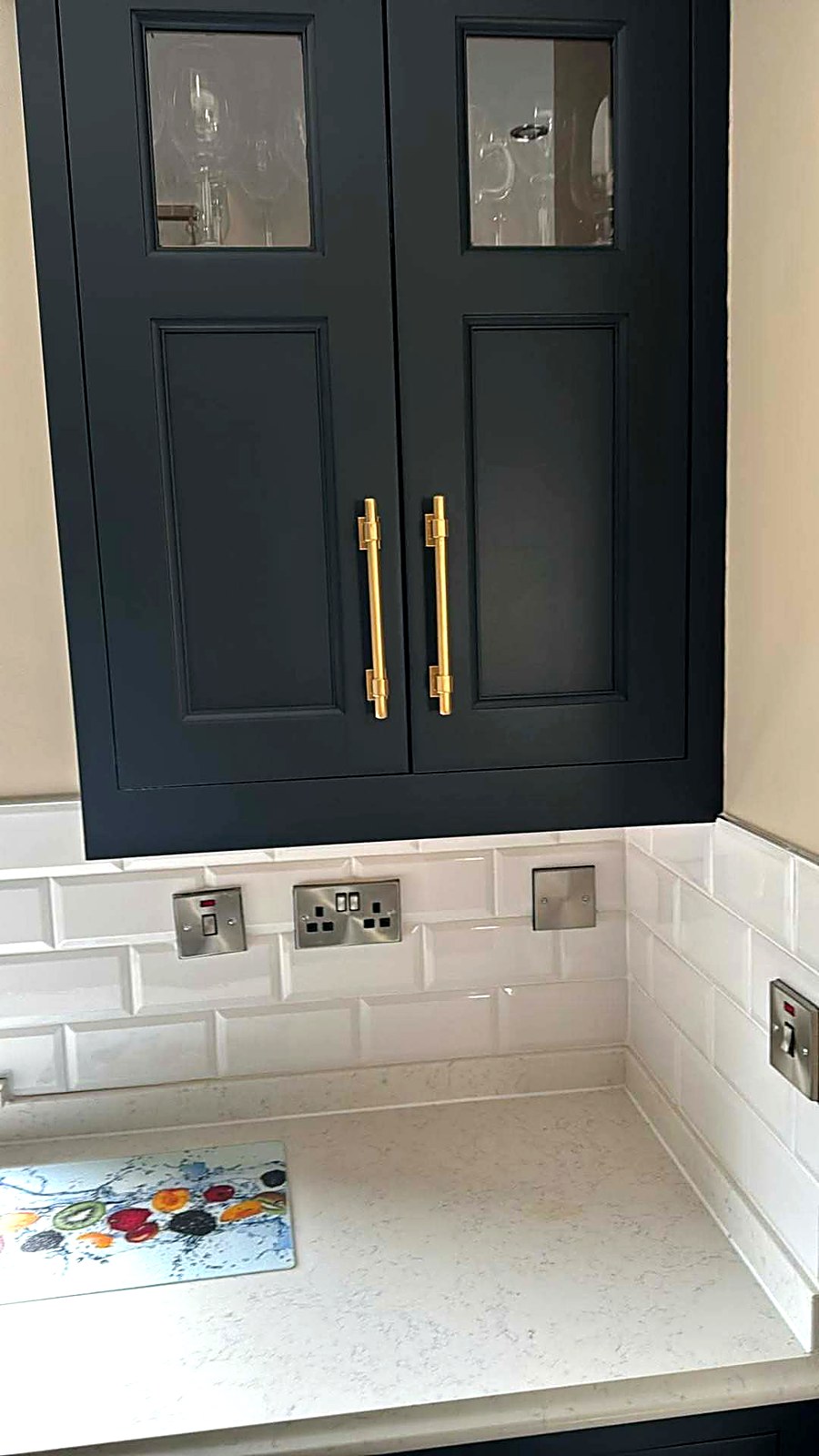 Navy painted wall units above a white metro tile splashback