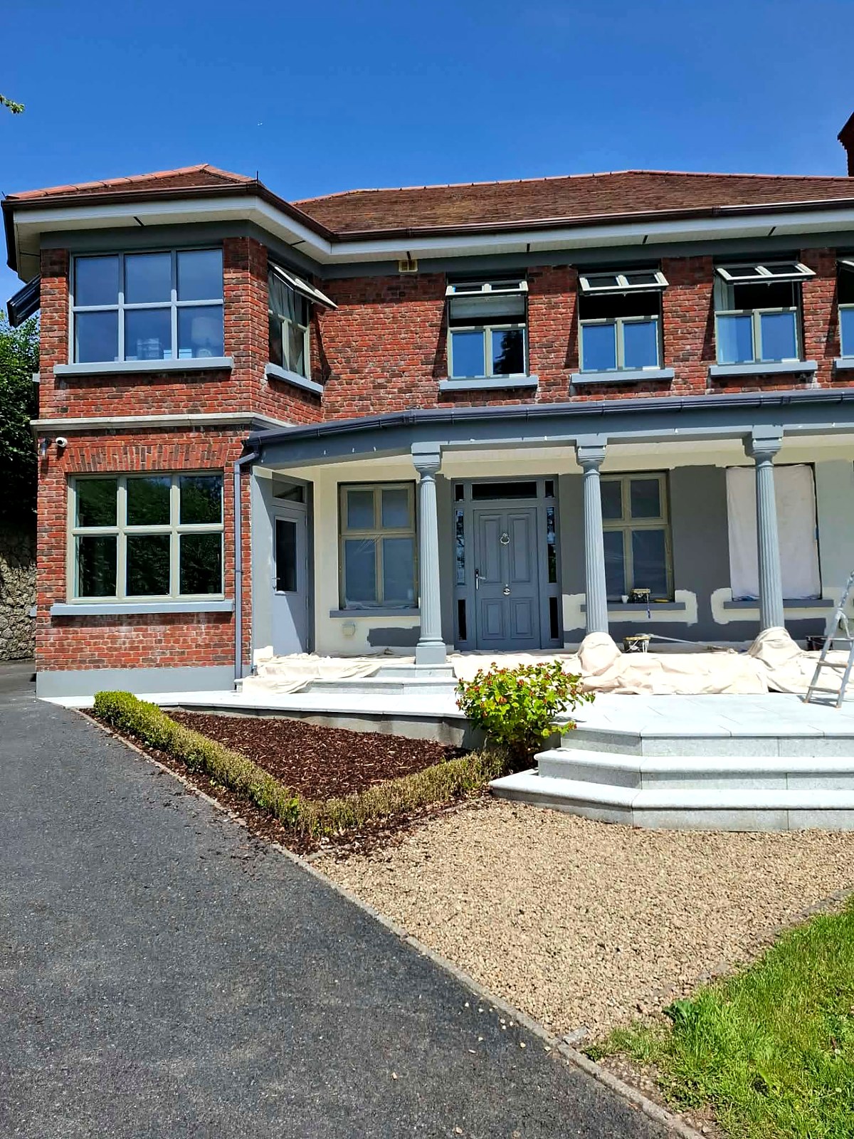 Front elevation mid-job with primed patches and freshly coated grey window frames