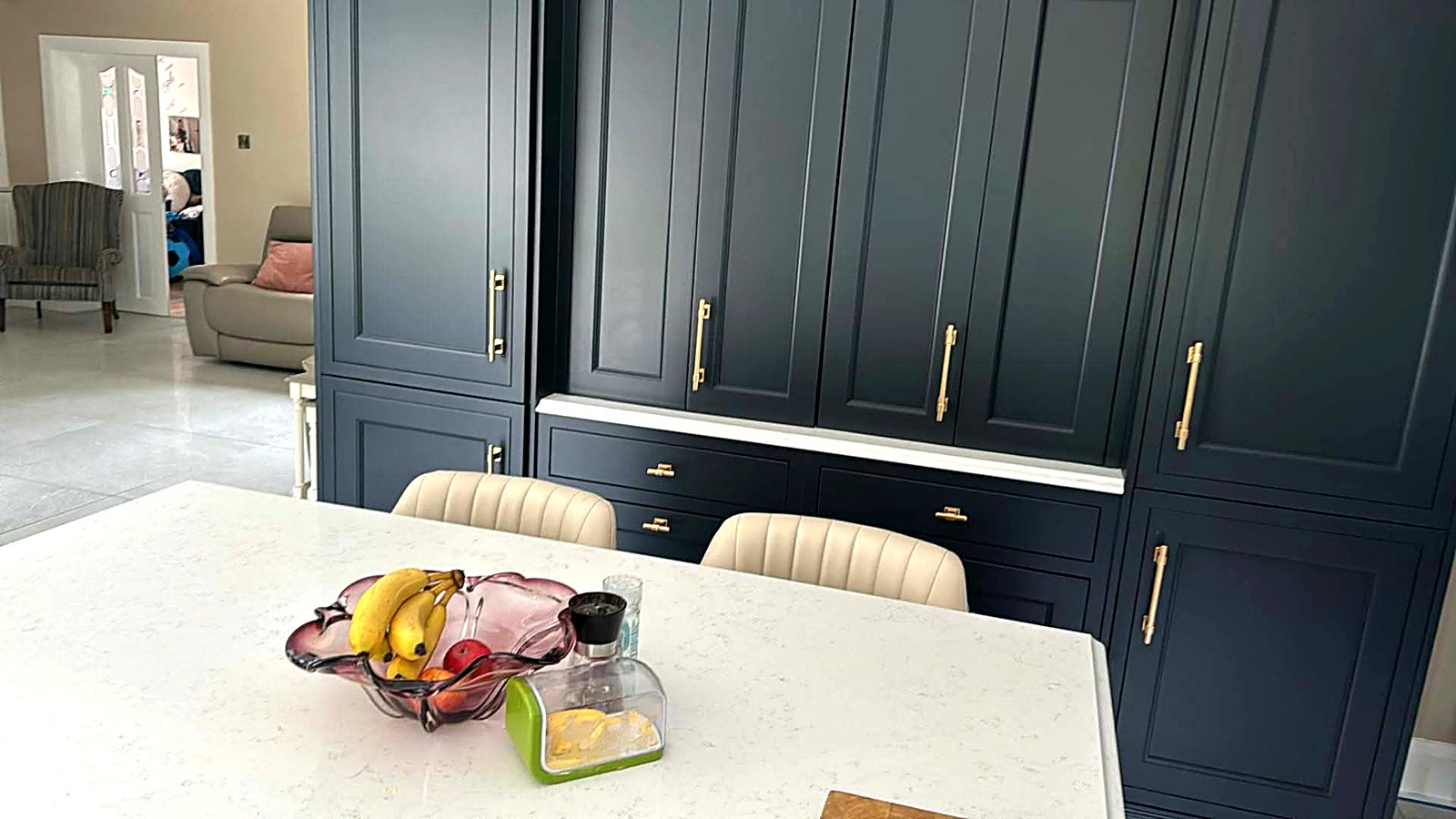 Floor-to-ceiling navy painted kitchen units with brass handles