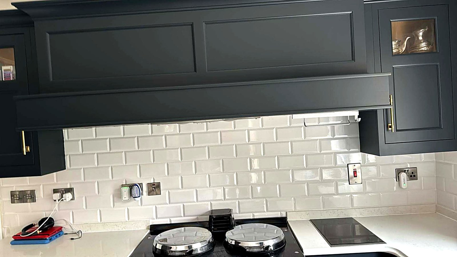Navy painted kitchen mantle hood over a metro tile splashback
