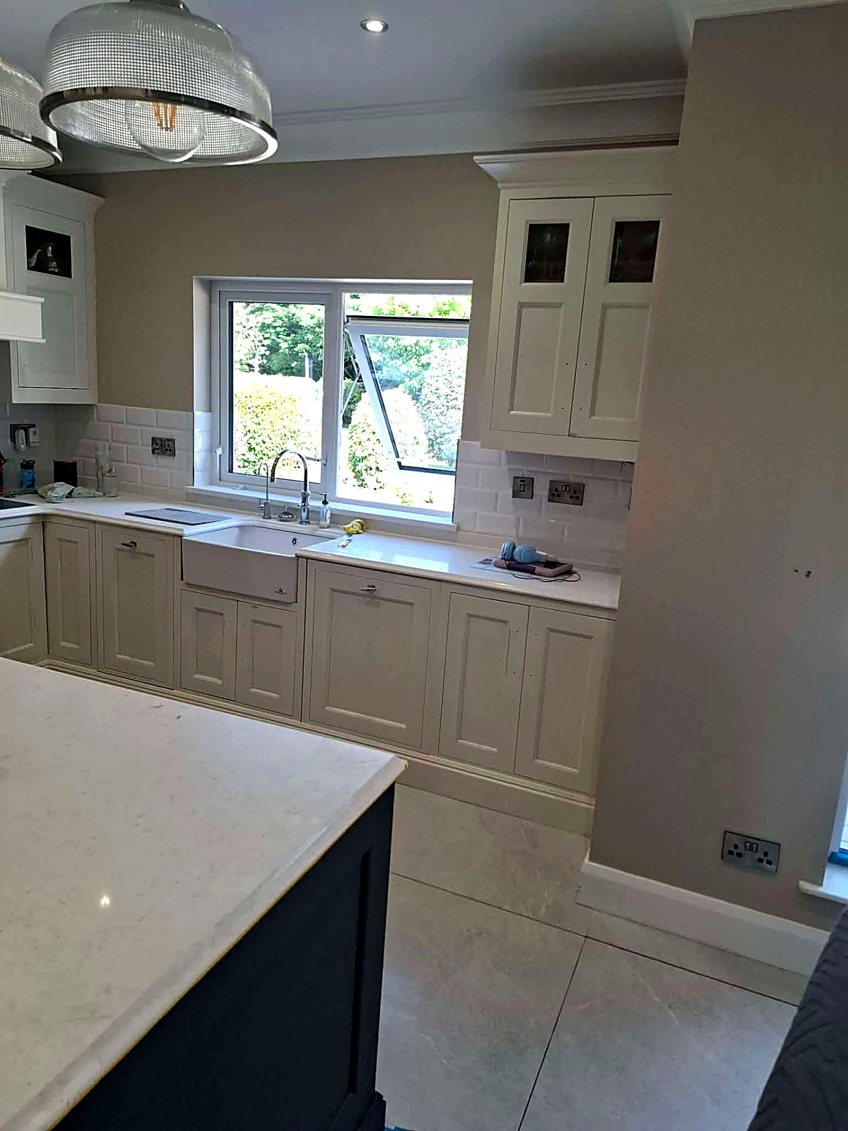 Cream painted kitchen units around a belfast sink and window