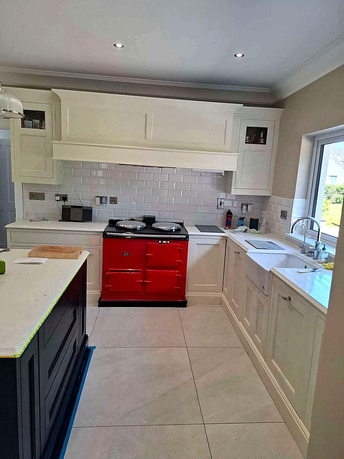 Cream painted kitchen with mantle hood over a red range cooker